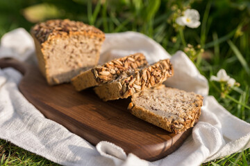 homemade grey bread with seeds on the wood board with the white cloth napkin on the green grass. High quality photo