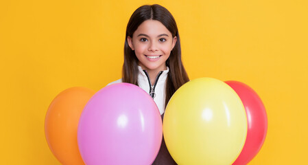 Fototapeta na wymiar happy kid with party colorful balloons on yellow background