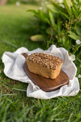 homemade grey bread with seeds on the wood board with the white cloth napkin on the green grass. High quality photo