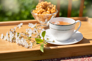 tea with pastries chak-chak in the cherry orchard on a sunny day, summer outdoor recreation. Chair with a tray among flowers and fruit trees