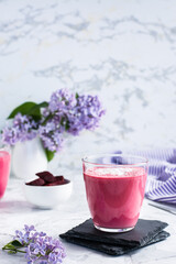 Sweet beetroot latte in a glass and beets in a bowl on the table. Vertical view