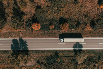 Aerial shot of freight transportation truck on road in summer afternoon, top down drone image