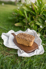 homemade grey bread with seeds on the wood board with the white cloth napkin on the green grass. High quality photo