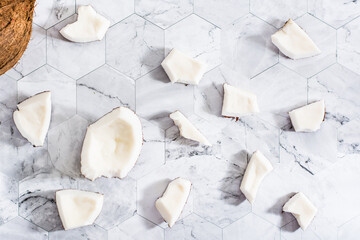 Pieces of coconut randomly arranged on a marble background. Natural antioxidant. Top view.