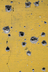 Holes from gunshots and shrapnel on a concrete wall n the war zone in Ukraine.