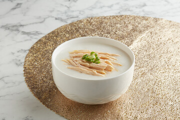Shredded Steamed Chicken Congee served in a bowl side view on grey marble background traditional vietnamese food
