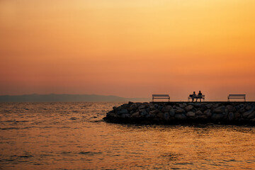 Obraz premium couple relaxing and watching the sea sunset