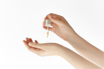 female hands hold a pipette with oil or extract on a white background, test cosmetic product