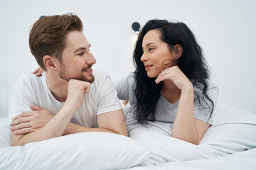 Happy young Caucasian couple resting in bedroom
