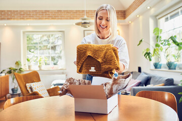 Mid adult woman unpack box with clothes. Online shopping concept - obrazy, fototapety, plakaty