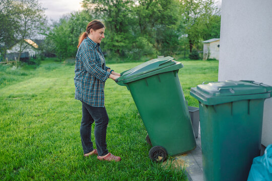 Plastic pollution problem. European 20s girl take out the trash can sorting garbage near a home. Put trash in garbage containers. Volunteers and responsible society.