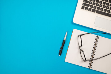 Top view of a laptop with a notepad pen and glasses