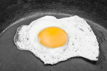 scrambled eggs in a cast iron skillet. Isolated on dark painted wood from above.