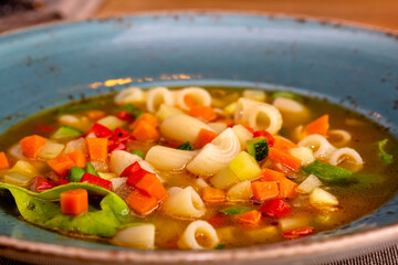 A bowl of minestrone soup with crackers on rustic vintage background