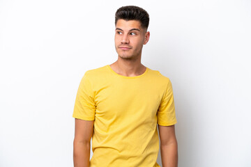 Young caucasian man isolated on white background making doubts gesture looking side