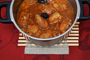 Meat with plums on the red background