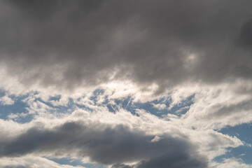 Dark clouds storm rain clouds with a gap where the sun shines view from below as a background.
