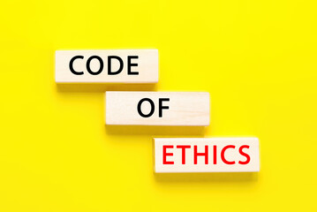 Code of ethics symbol. Concept words Code of ethics on wooden blocks on yellow background. Business...