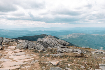 Beautiful mountain landscape with sharp large stones and mountain plants against the blue sky with clouds