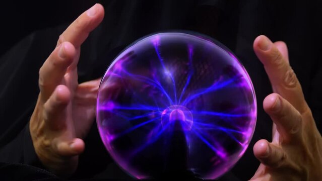 The witch looks inside the magic ball of destinies and moves her hands over it to perform a magic ritual..
