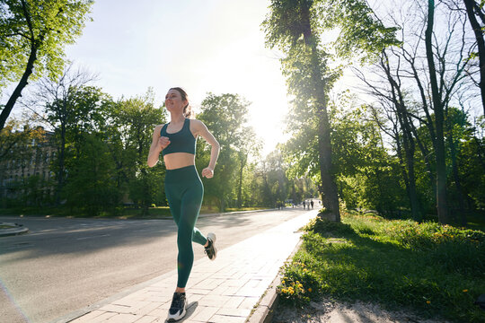 Slim female enjoying jogging during free time in park