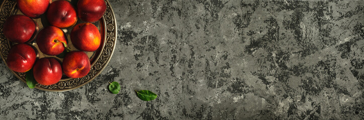 Fresh organic nectarines on a plate top view. Dark motley background with copy space. and selective focus.Banner