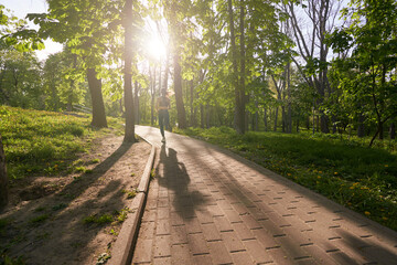 Slim woman going running in nature on sunny day