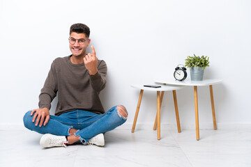 Young caucasian man sitting in his home isolated on white background doing coming gesture