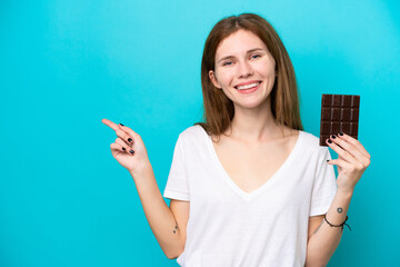 Young English woman with chocolat isolated on blue background pointing finger to the side