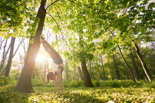Sporty female doing acrobatic exercises in forest