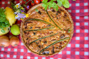 Quiche Lorraine Tart. Egg and cheese tart on pastry crust filled with savoury custard and pieces of cheese, bacon, and asparagus.