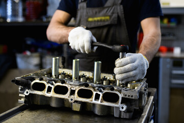 Partial shot of auto mechanic in gloves using ratchet tool while fixing damaged car engine 