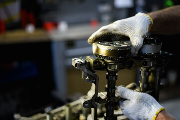 Faceless shot of auto mechanic working with damaged camshafts in garage 