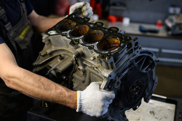 Partial view of auto mechanic holding damaged car engine in service station 