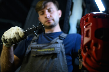 Blurred auto mechanic holding caliper near disc brake in garage 