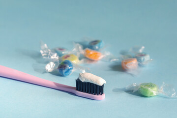 toothbrush and candy caramel on a blue background, the concept of caries prevention.