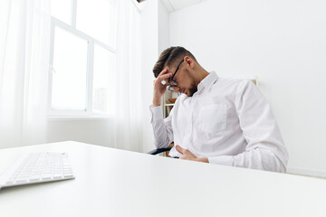 businessmen in a white shirt sits at a computer with a phone office