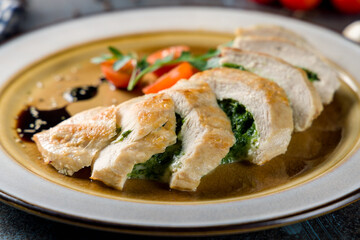chicken fillet with spinach on plate on blue concrete table macro close up
