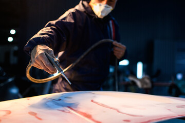 Partial view of workman cleaning dust from car part with compressor in garage 