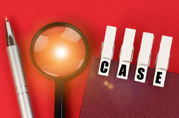 On the red surface there is a magnifying glass, a notepad and clothespins with the inscription -...