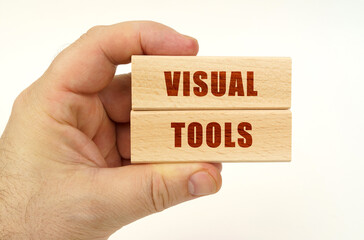 On a white background, a hand that holds wooden blocks with the inscription - Visual Tools