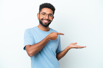 Young Brazilian man isolated on white background holding copyspace imaginary on the palm to insert an ad