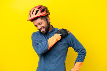 Young cyclist Brazilian man isolated on yellow background suffering from pain in shoulder for having made an effort