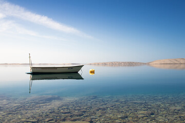 Fisher boat in calm water with blue sky and mountains