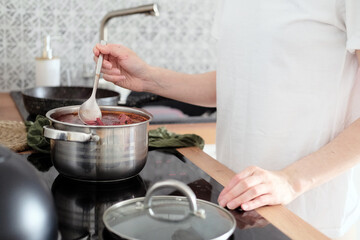 Obraz na płótnie Canvas Woman cooking soup in the kitchen