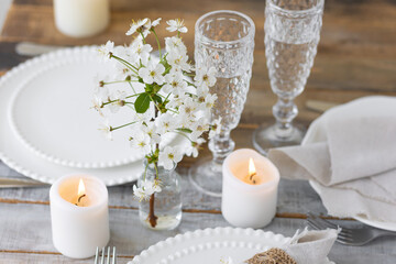 Rustic zero waste wedding decor with natural elements. Wooden table, candles, linen napkins, branches with green leaves. Eco-friendly decoration for the special dinner. Romantic and cozy place
