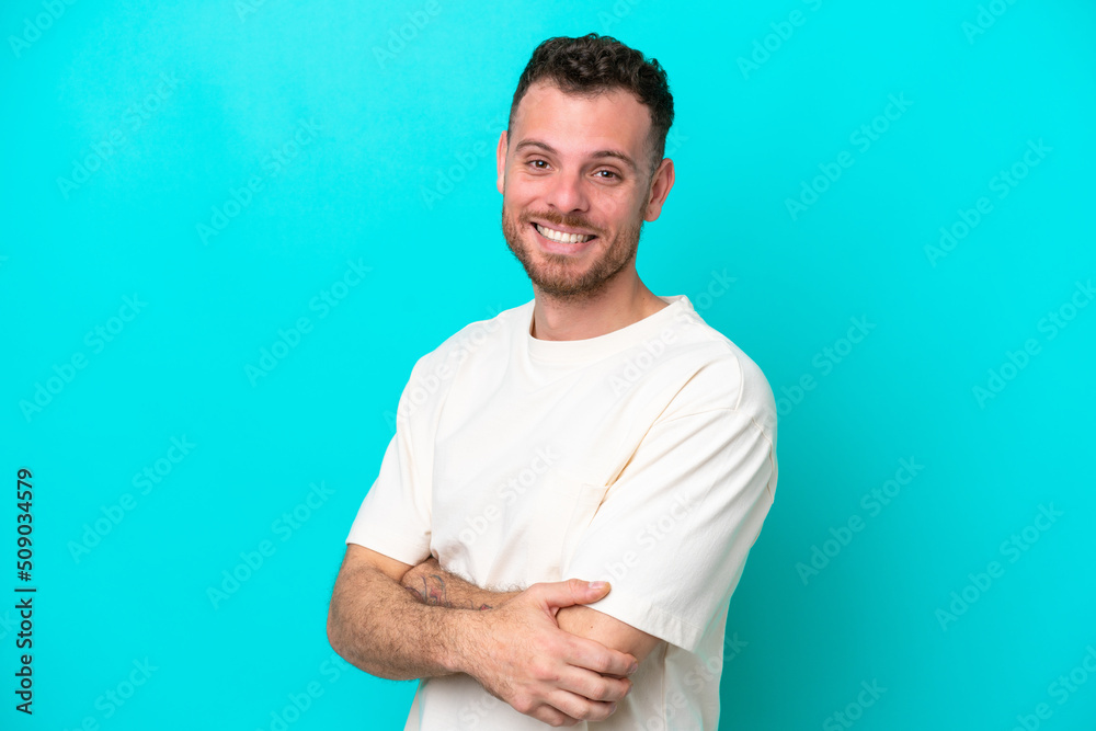 Wall mural young brazilian man isolated on blue background with arms crossed and looking forward