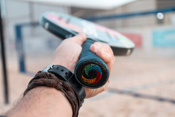 Beach tennis racket in hand. Hand with bracelets.