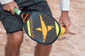 Man holding beach tennis racket and ball in hands