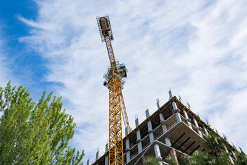 Fototapeta na wymiar A construction crane works on the construction site of a multi-storey building.